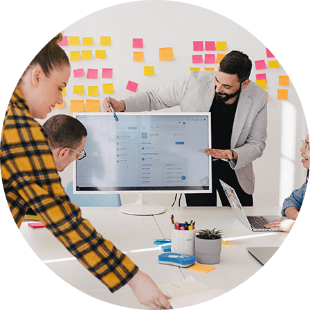 A team collaborating around a screen, brainstorming with sticky notes on the wall in a creative workspace.